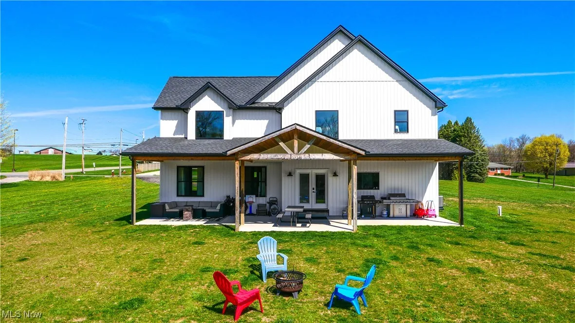 Rear view of property featuring a yard, an outdoor living space with a fire pit, a patio, and french doors