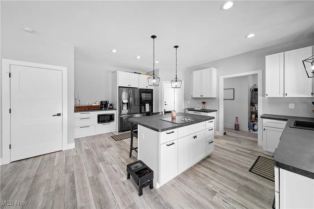 Kitchen with dark countertops, recessed lighting, and black appliances