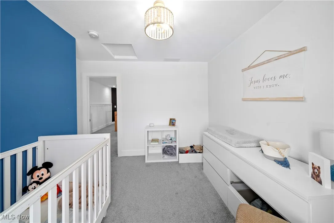 Carpeted bedroom featuring a nursery area