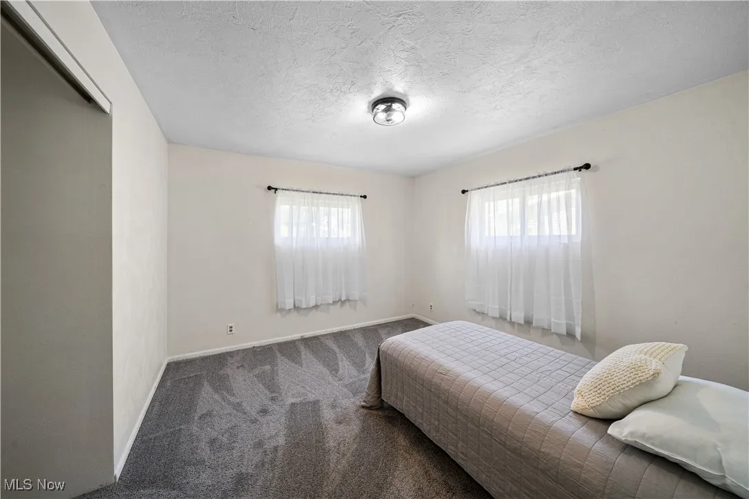 Carpeted bedroom featuring baseboards and a textured ceiling