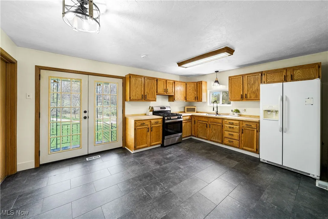 Kitchen with gas range, a wealth of natural light, white fridge with ice dispenser, and light countertops