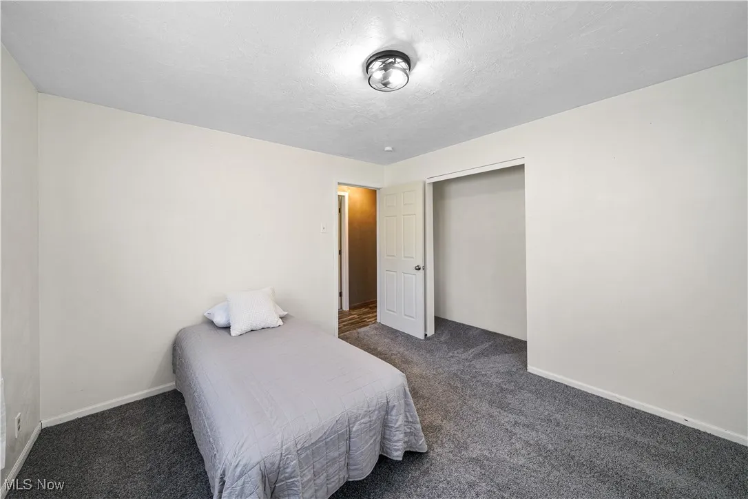 Bedroom featuring dark carpet, baseboards, and a textured ceiling