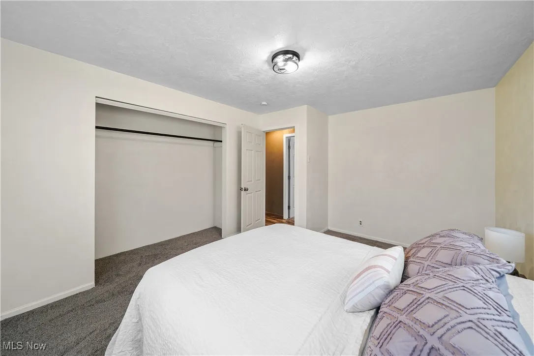 Carpeted bedroom featuring a textured ceiling, a closet, and baseboards
