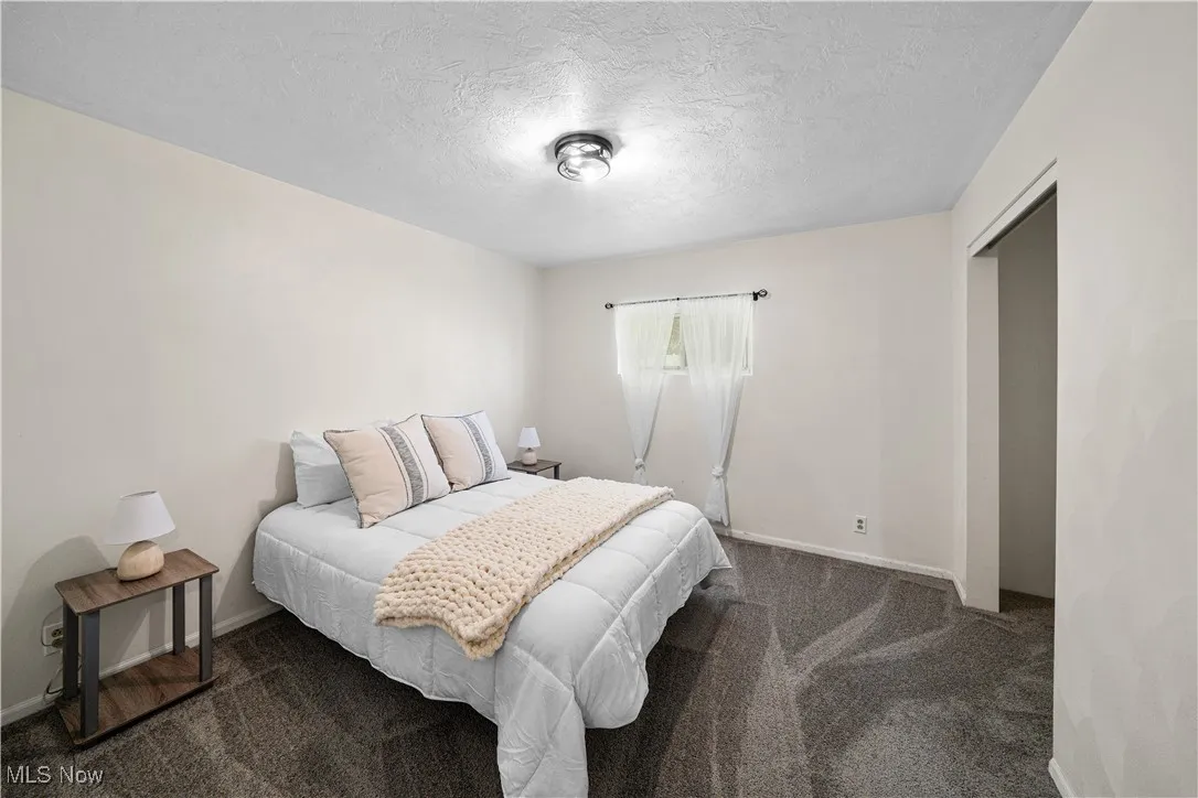 Carpeted bedroom featuring baseboards and a textured ceiling