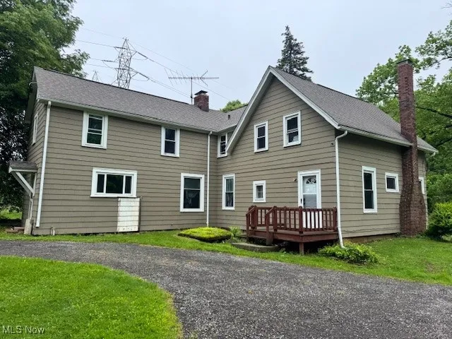 Back of property with a wooden deck, a chimney, and a yard