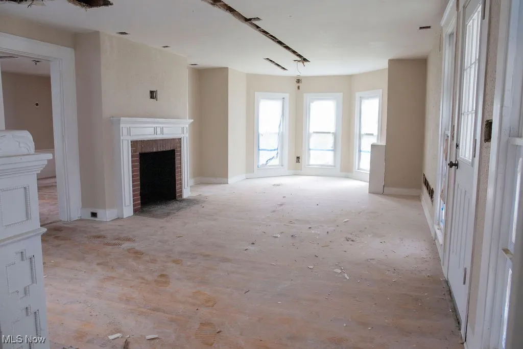 Unfurnished living room with baseboards and a brick fireplace