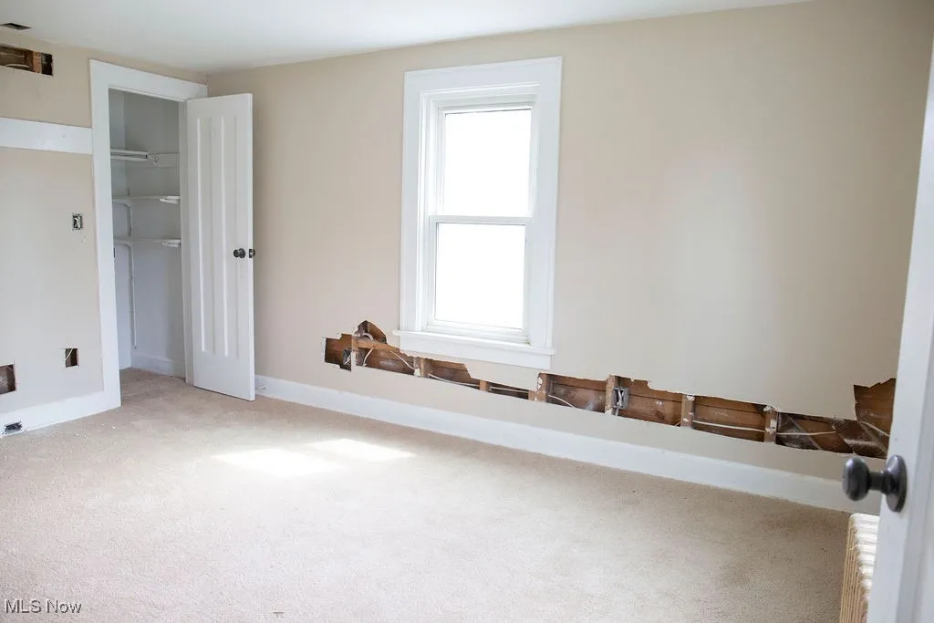 Unfurnished bedroom with baseboards, a closet, and light colored carpet