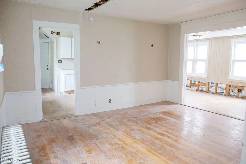 Spare room with wainscoting, a textured wall, and wood finished floors