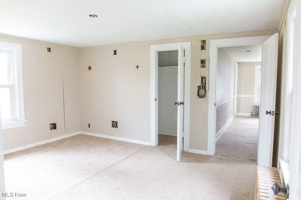 Unfurnished bedroom with baseboards, a closet, and light colored carpet