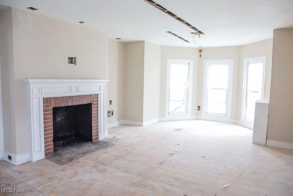 Unfurnished living room with baseboards, visible vents, and a fireplace