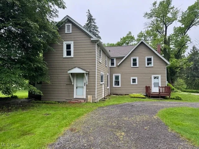 Back of property with a wooden deck, a chimney, and a yard