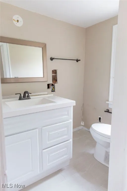 Bathroom with toilet, vanity, and tile patterned floors