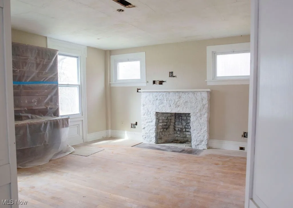 Unfurnished living room featuring plenty of natural light, wood finished floors, and a fireplace