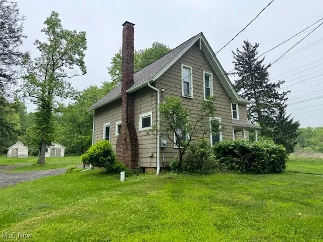 View of side of property with a chimney and a lawn