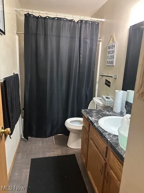 Full bathroom featuring baseboards, vanity, curtained shower, and toilet