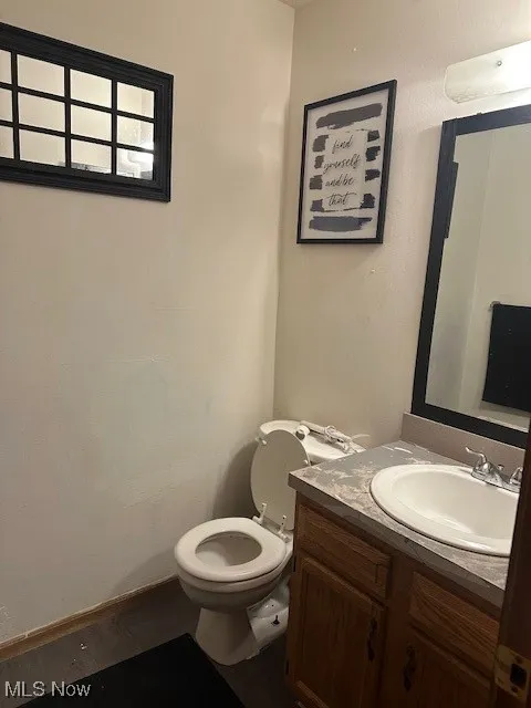 Half bathroom with wood finished floors, vanity, and toilet