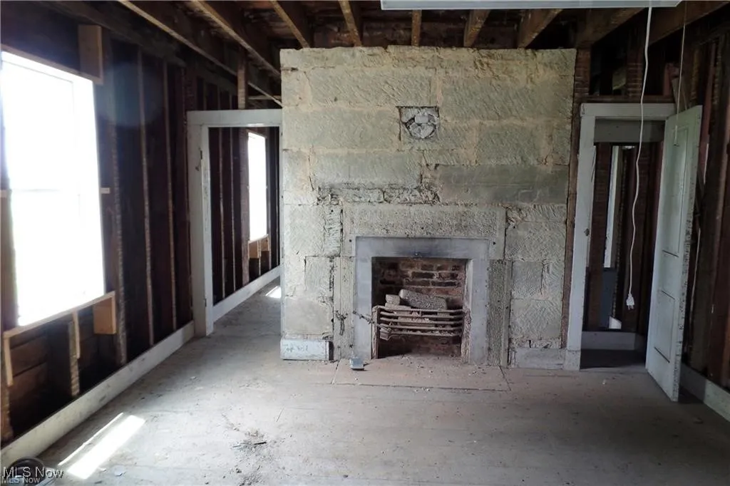 Unfurnished living room featuring a stone fireplace