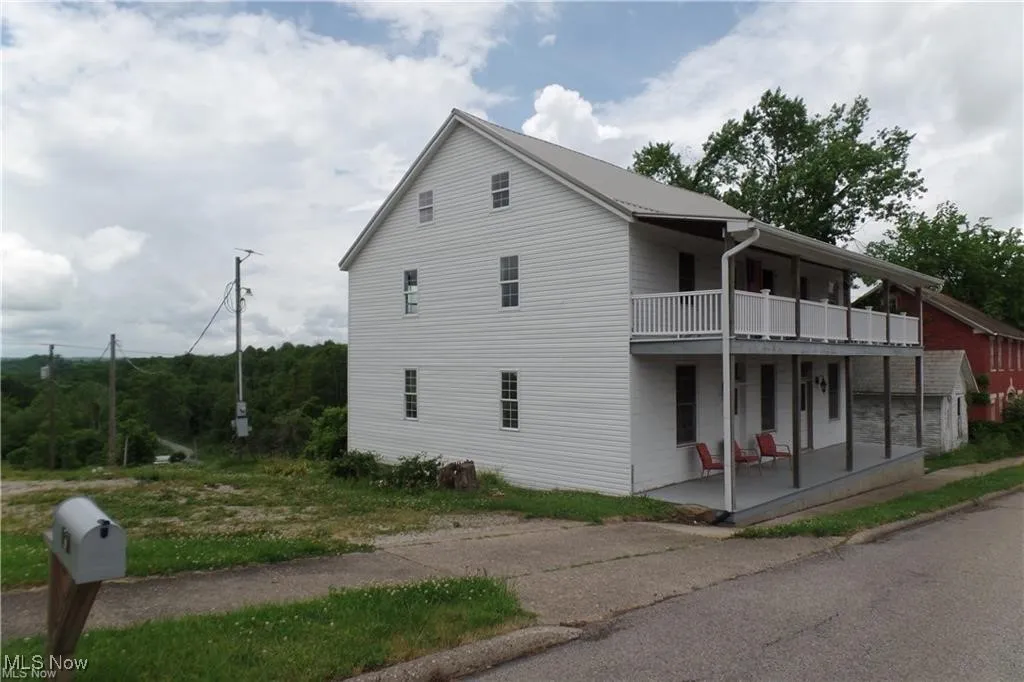 View of property exterior featuring covered porch and a balcony