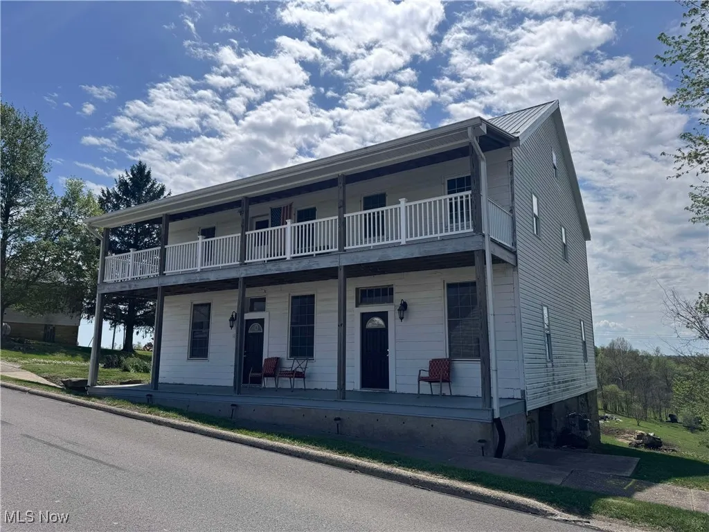 View of property with a porch, a balcony, and metal roof