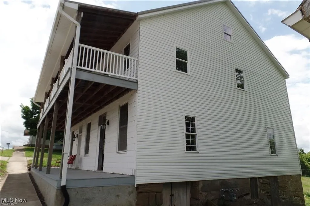 View of side of home featuring covered porch and a balcony