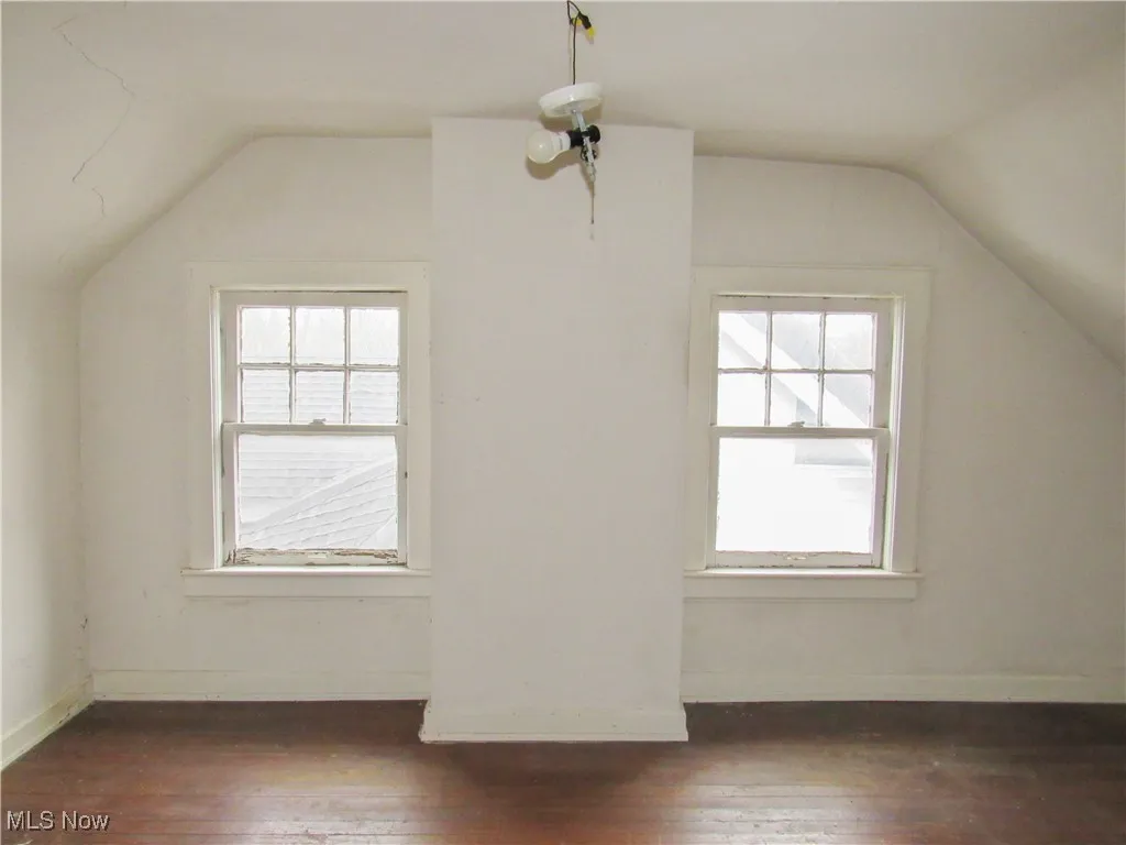 Additional living space with lofted ceiling, a healthy amount of sunlight, and dark wood finished floors
