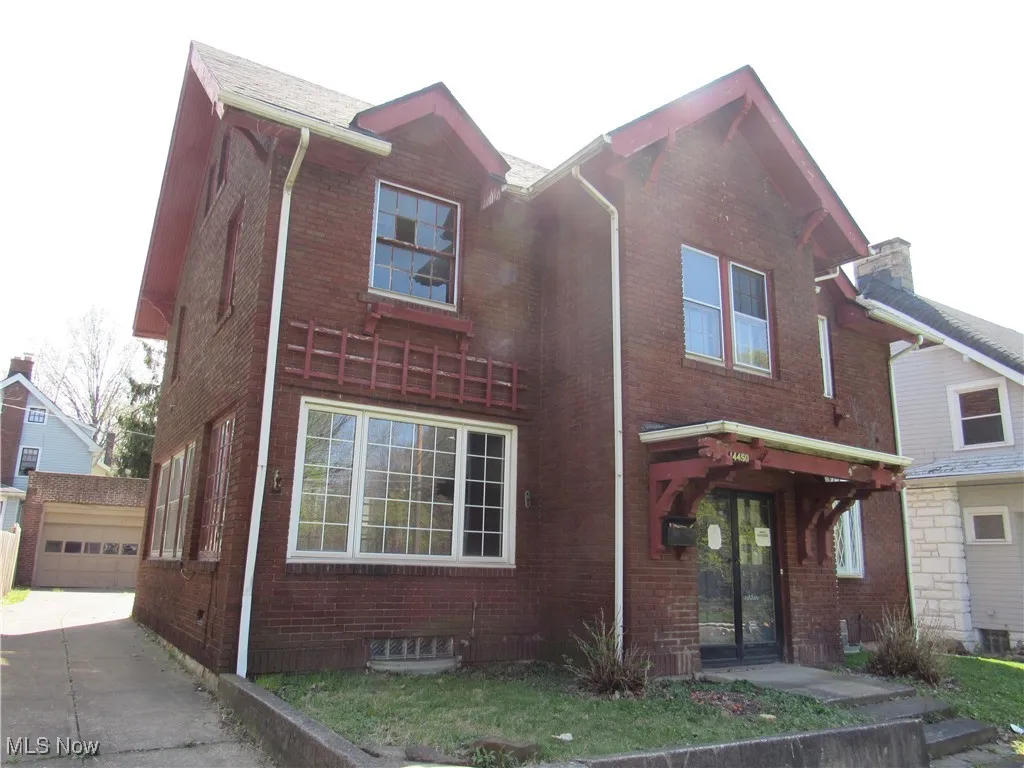View of front of house with brick siding, driveway, a garage, and an outdoor structure