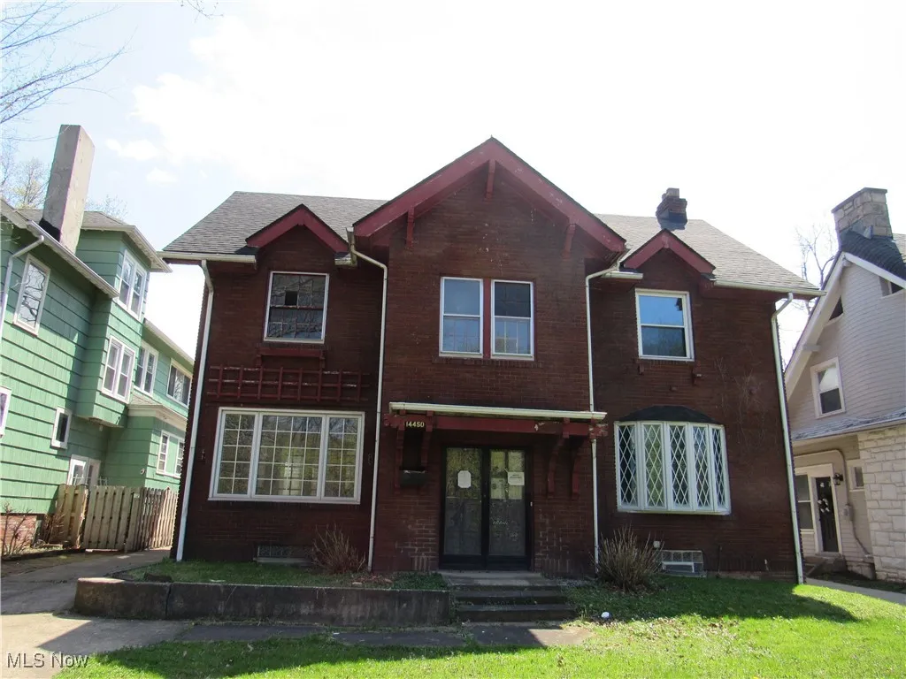 View of front of home featuring brick siding, a front yard, and french doors