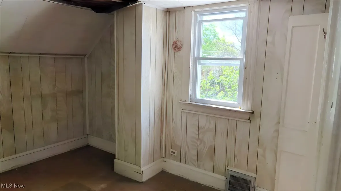 Bonus room with wooden walls, baseboards, and visible vents