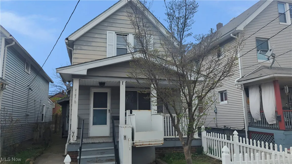 Shotgun-style home featuring a porch and fence