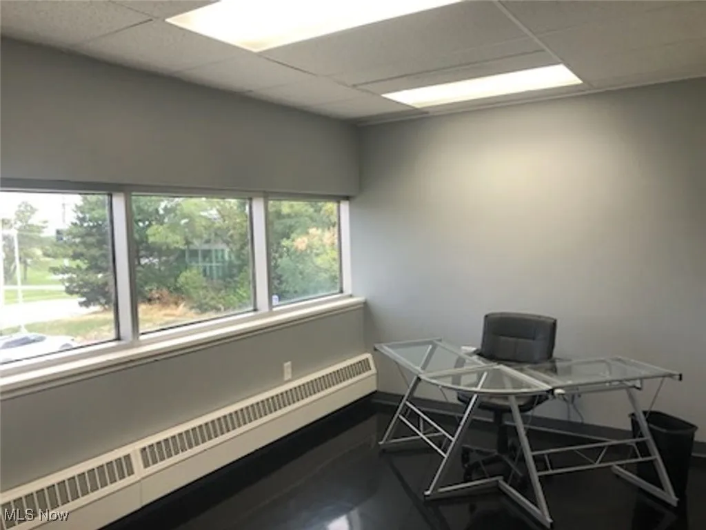 Office area featuring baseboard heating, baseboards, and a drop ceiling