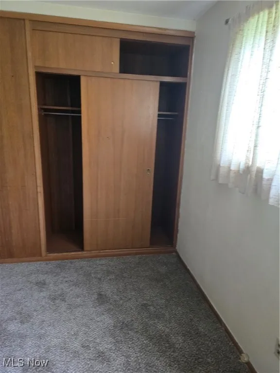 Unfurnished bedroom with a closet, carpet, and baseboards