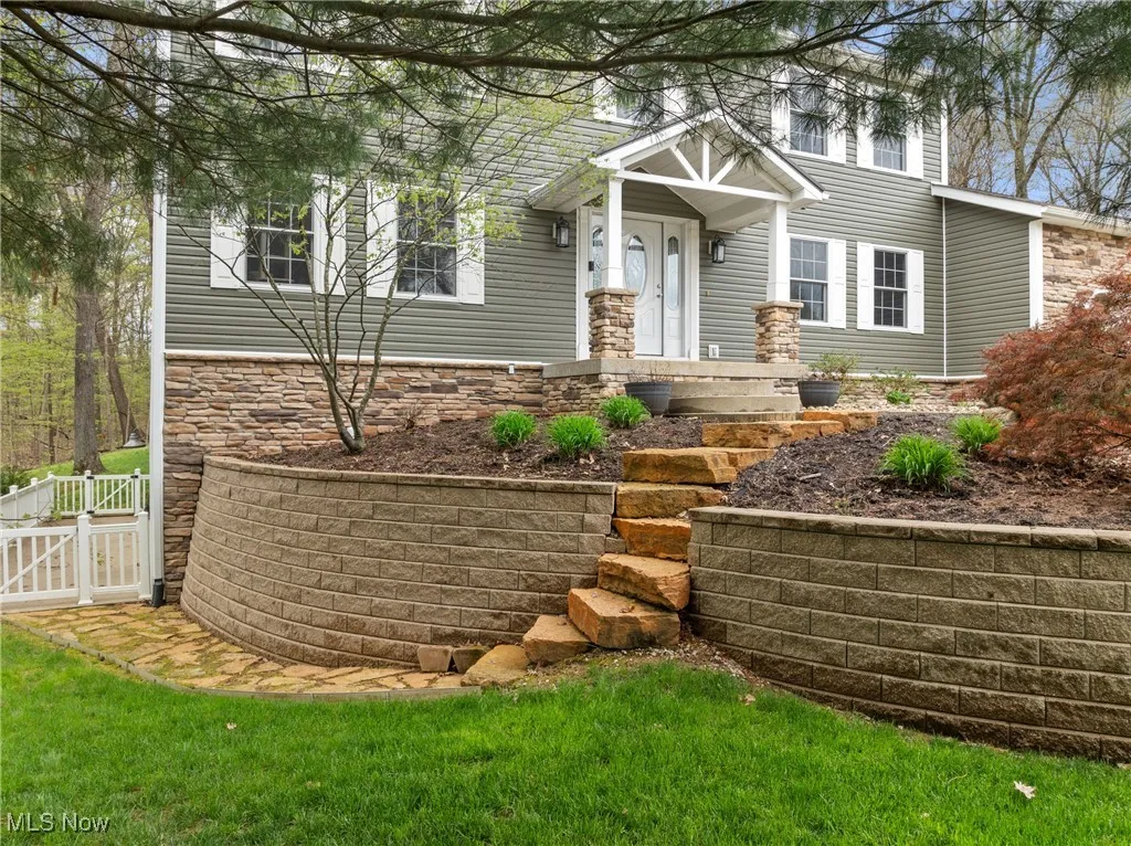 View of front of house featuring fence, a gate, and stone siding