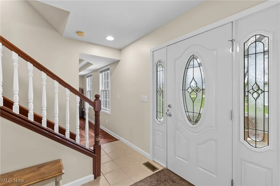 Foyer featuring recessed lighting, light tile patterned floors, stairs, visible vents, and baseboards