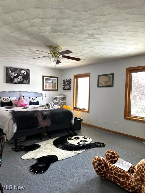 Carpeted bedroom with baseboards and a ceiling fan