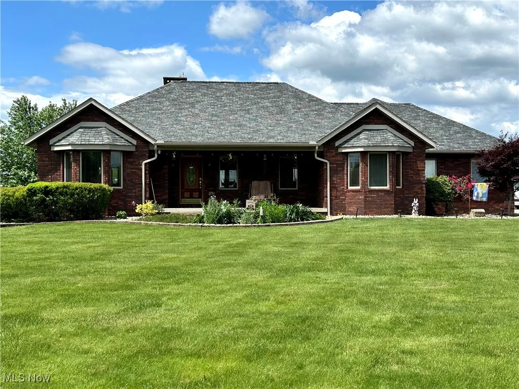 View of front facade with a front lawn, brick siding, and covered porch