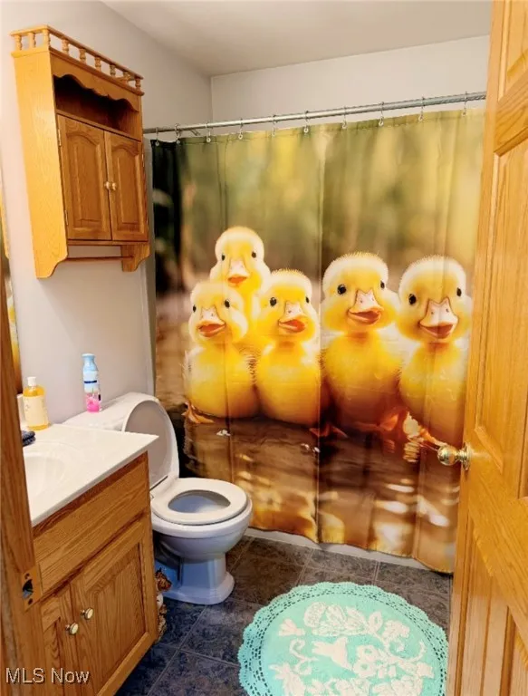 Full bath featuring toilet, a shower with curtain, vanity, and tile patterned floors
