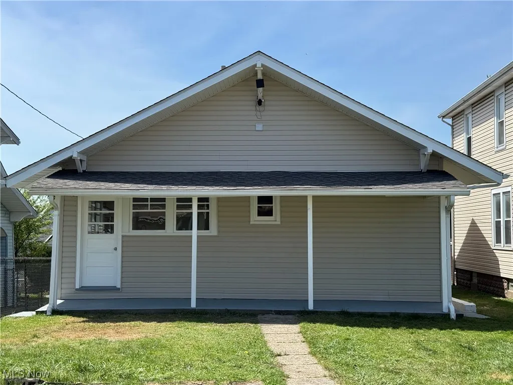 Rear view of property featuring a lawn and roof with shingles