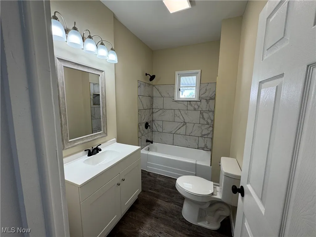 Bathroom featuring toilet, vanity, wood finished floors, and tub / shower combination