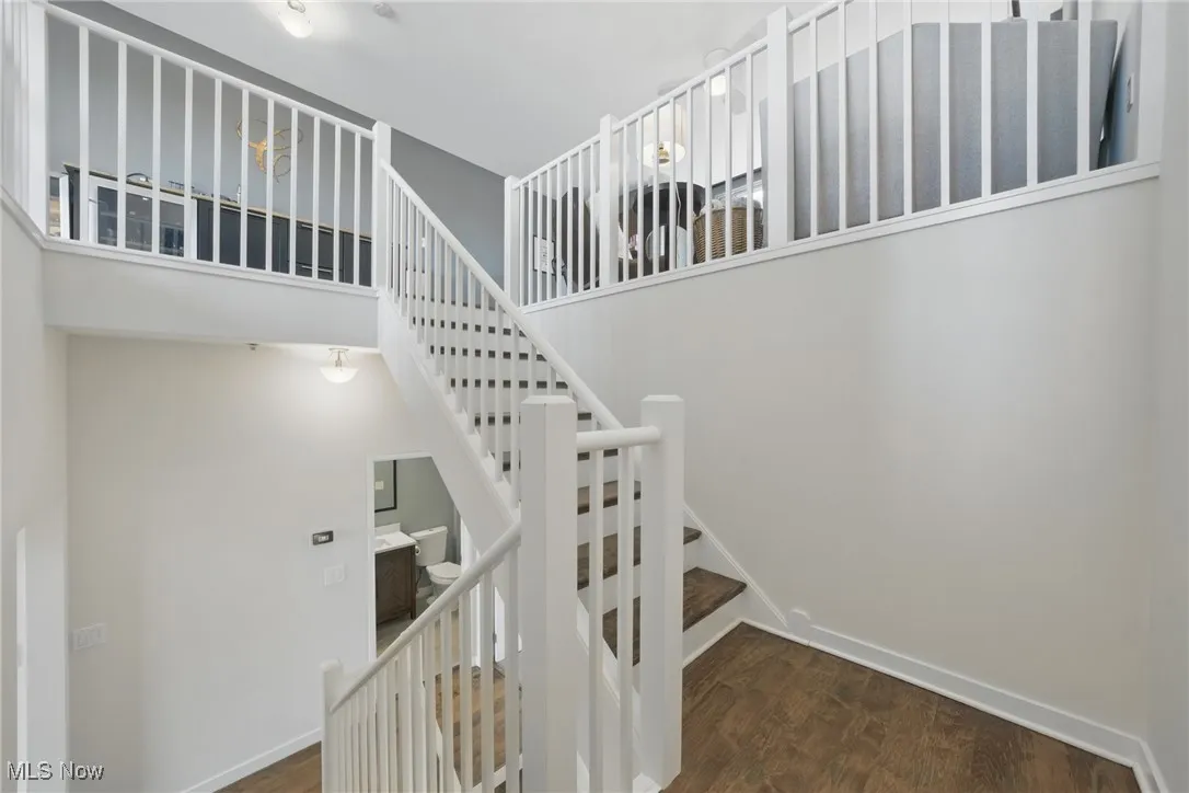 Stairs featuring wood finished floors, a towering ceiling, and baseboards