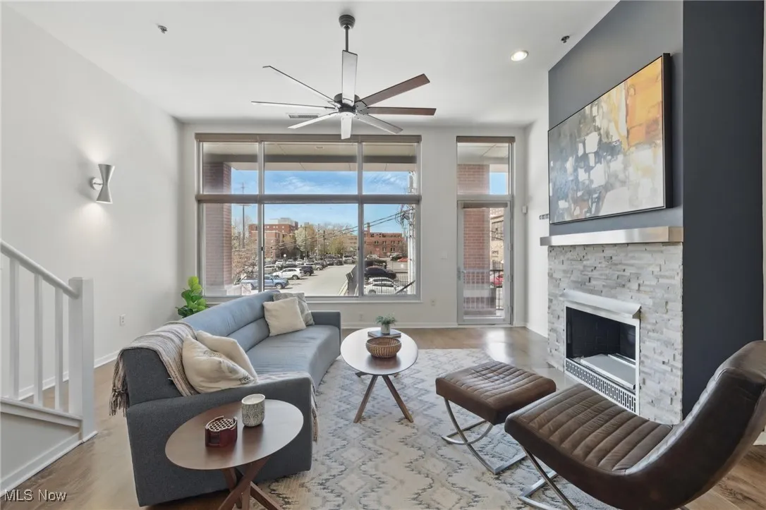Living area with stairway, wood finished floors, ceiling fan, a fireplace, and baseboards