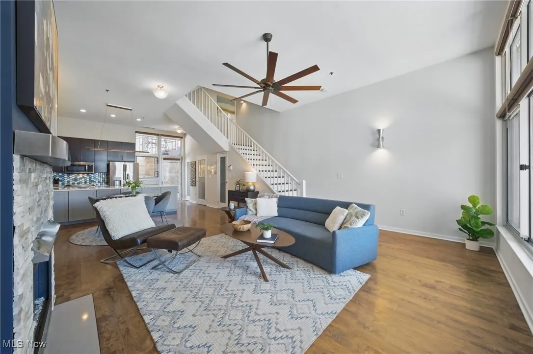Living room with stairway, a ceiling fan, baseboards, and wood finished floors