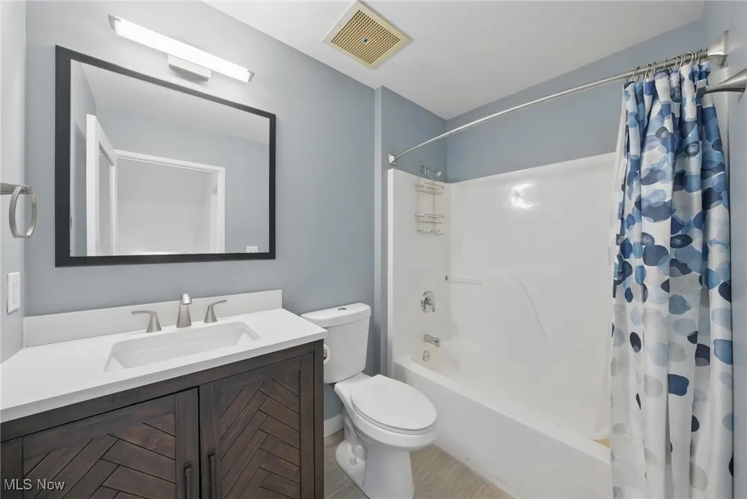 Full bath featuring tile patterned flooring, visible vents, toilet, vanity, and shower / tub combo with curtain