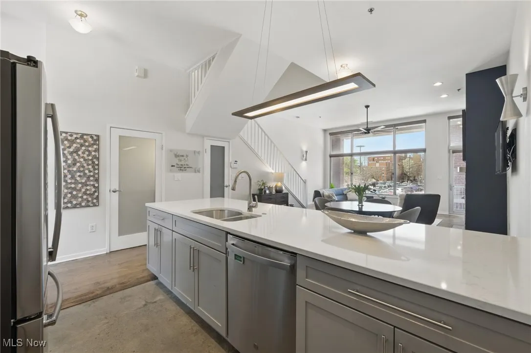 Kitchen featuring a sink, open floor plan, gray cabinets, ceiling fan, and stainless steel appliances