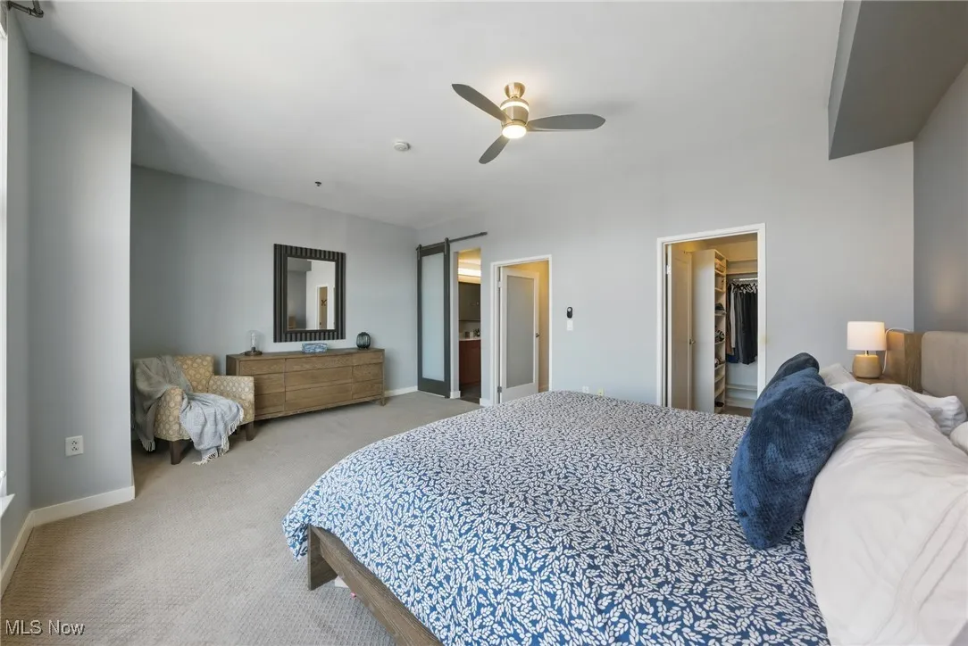 Carpeted bedroom featuring a walk in closet, baseboards, and ceiling fan