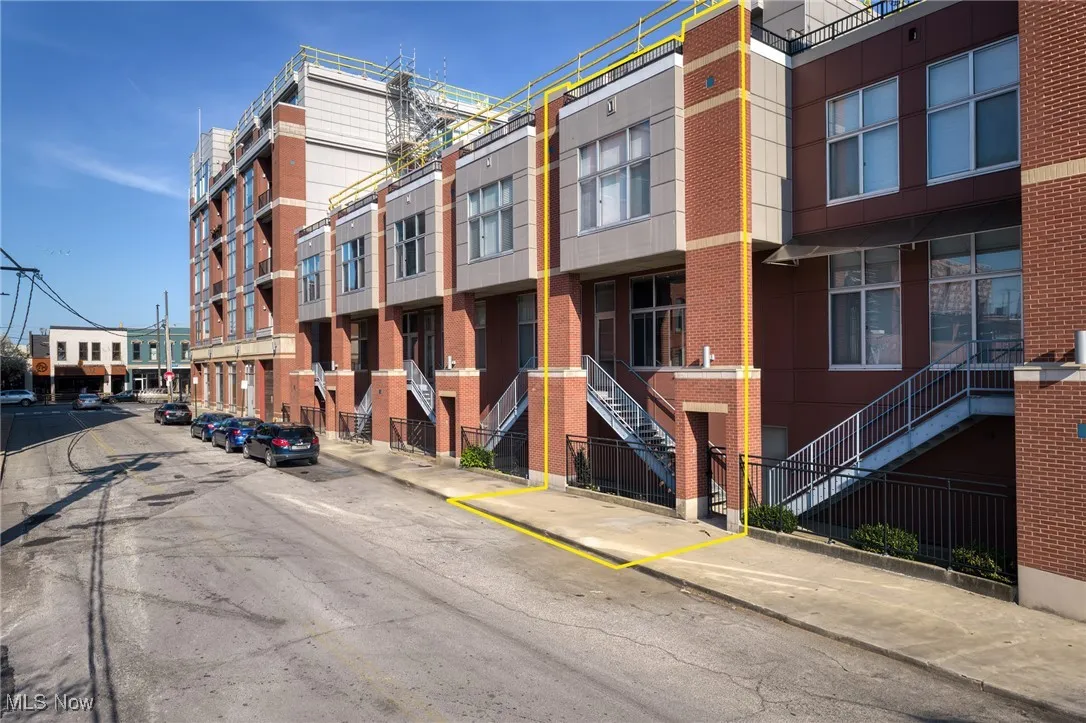 View of property with uncovered parking and stairs