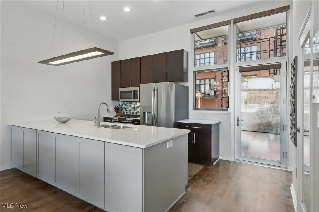 Kitchen with a peninsula, dark wood-style floors, a sink, visible vents, and appliances with stainless steel finishes