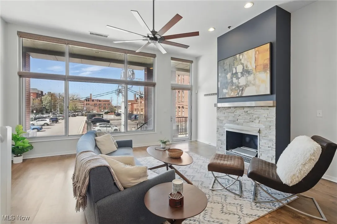 Living area featuring a ceiling fan, wood finished floors, visible vents, and a fireplace
