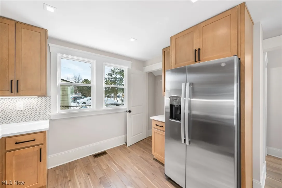 Kitchen featuring stainless steel fridge with ice dispenser, visible vents, light wood finished floors, and baseboards
