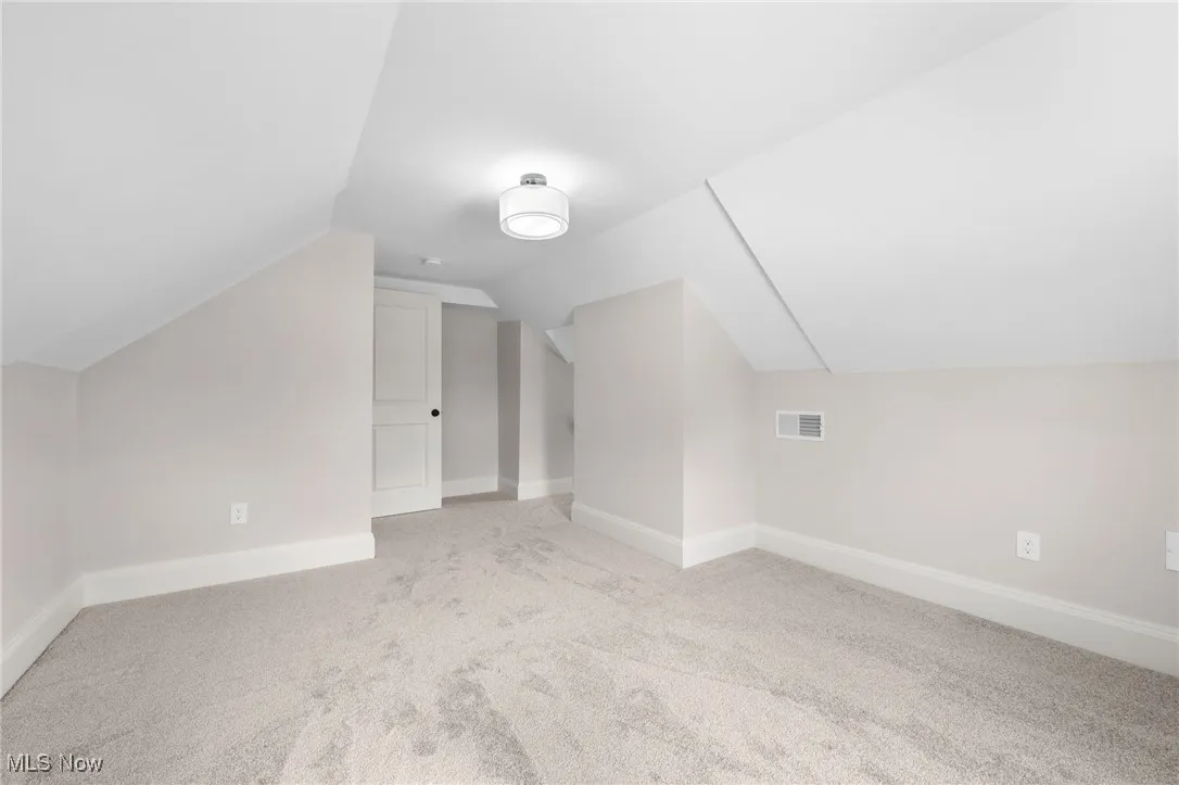 Bedroom featuring carpet floors, vaulted ceiling, and baseboards