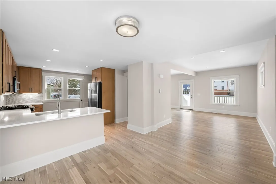 Kitchen with a peninsula, a sink, open floor plan, brown cabinetry, and appliances with stainless steel finishes